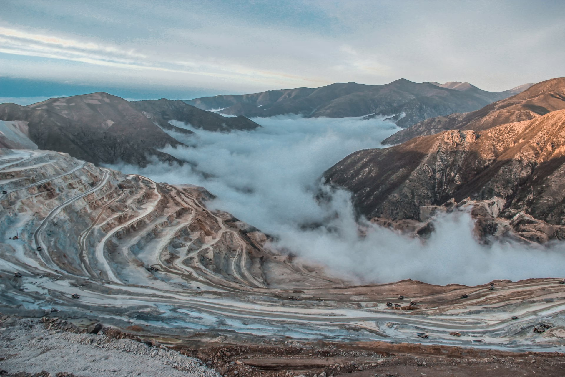A large open-pit mining operation nestled within mountainous terrain